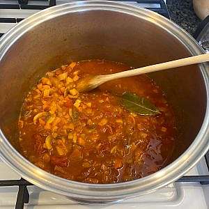 Cooking soup base with vegetables in pot – carrots, peppers, mushrooms, paprika broth.