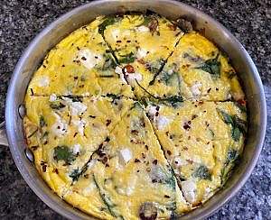 Golden Mediterranean frittata sliced into wedges in the skillet, ready to serve.