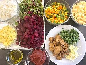 Ingredients for vegan borscht neatly arranged: diced vegetables, vegan sausage, herbs, and oil.