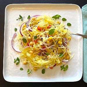Mediterranean spaghetti squash salad plated with fresh mint and red onion slices