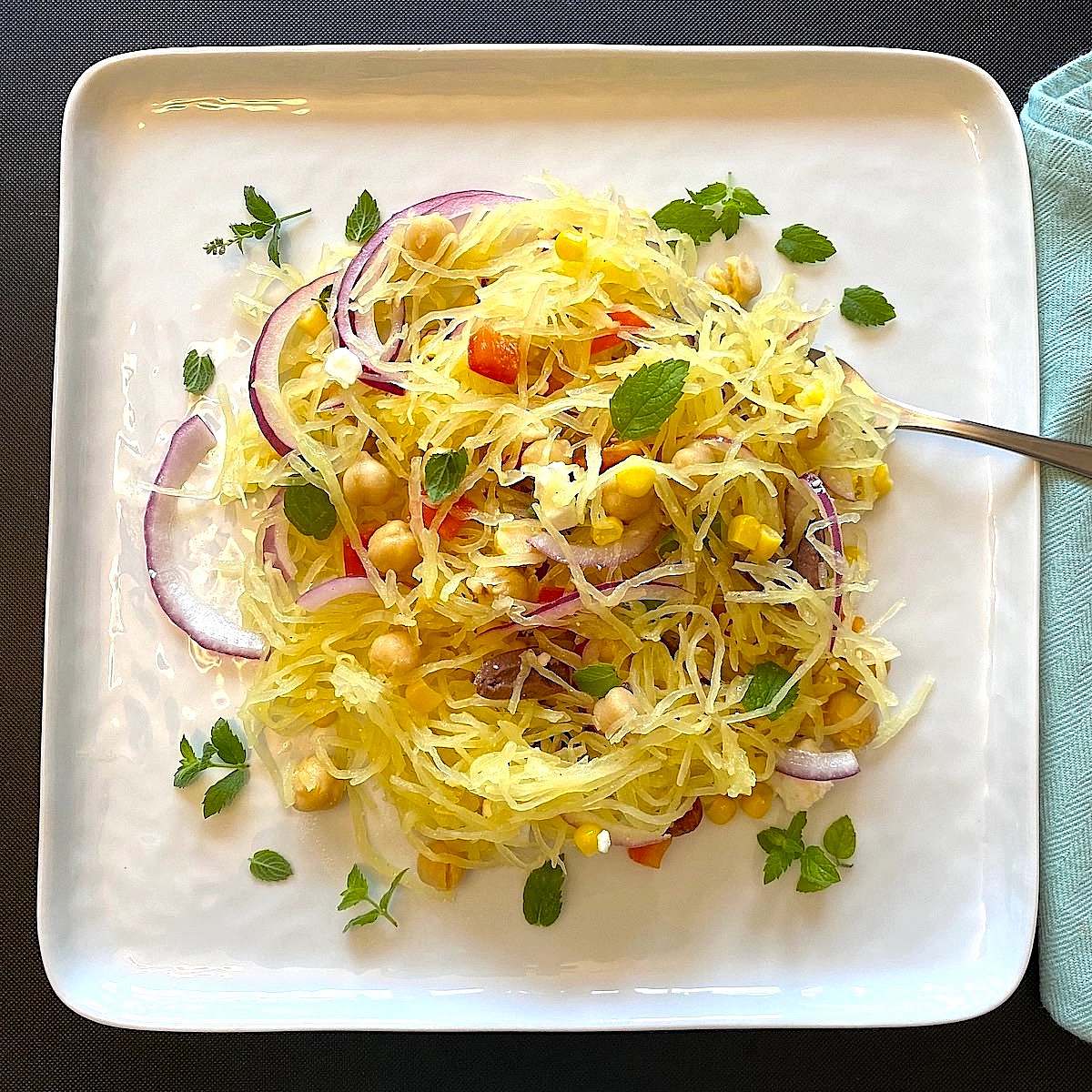 Mediterranean spaghetti squash salad plated with fresh mint and red onion slices