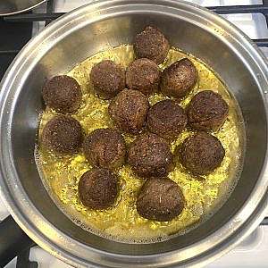 Pan-fried plant-based meatballs browning evenly in olive oil