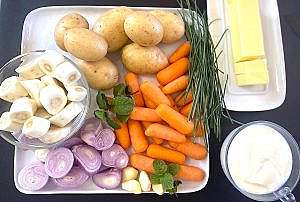 Prepared ingredients for silky carrot parsnip potato soup, including chopped parsnips, yellow potatoes, shallots, garlic, butter, yogurt, fresh herbs, and olive oil arranged before cooking