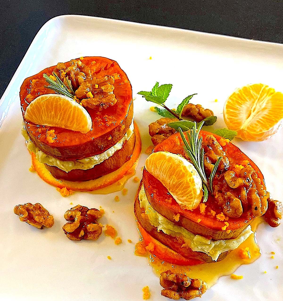Mediterranean-style sweet potato stacks garnished with rosemary, mint, and tangerine wedges